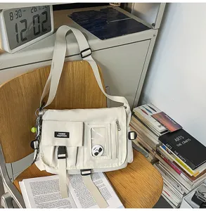 Detail view of a minimalist beige nylon student messenger bag with multi-pocket design