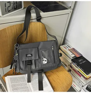 Versatile gray nylon messenger bag for students shown in a lifestyle desk setting