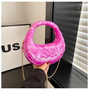 Close-up of pink acrylic handbag with marble texture and gold chain strap
