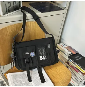 Black nylon messenger bag with workwear patches on a wooden chair lifestyle view