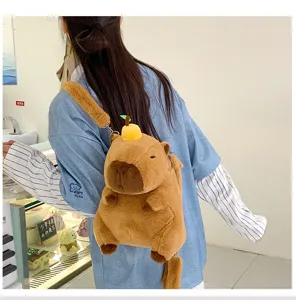 Close-up of a cute brown plush capybara backpack with a small yellow fruit on its head.