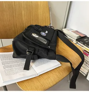 Detailed view of black nylon messenger bag with cargo buckle and decorative patch.