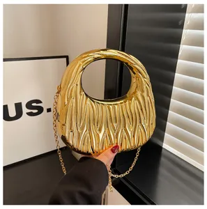 Close-up detail of a shiny golden acrylic handbag with unique wavy texture and metallic chain