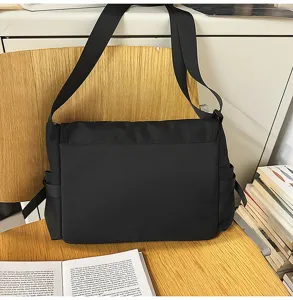 Black minimalist nylon messenger bag with adjustable shoulder strap and side pockets