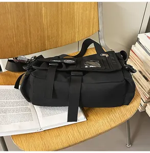 Detailed view of black nylon student messenger bag with buckle straps on a wooden chair