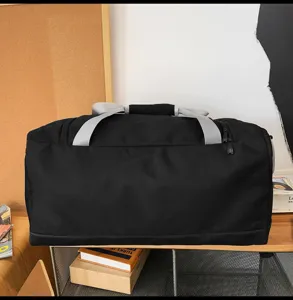 Borsone sportivo nero di grande capacità con cinghie grigie su uno scaffale in legno