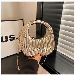 Detailed close-up of a gold metallic pleated handbag with a round handle and chain