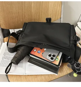 Detail view of black nylon messenger bag showing interior capacity with tablet and umbrella