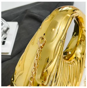Close-up detail of golden metallic ribbed handbag with shiny gold chain and clasp.