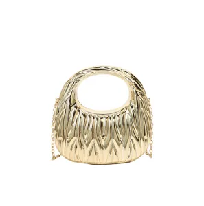 Close-up detail of the pleated metallic texture and circular handle on the gold handbag.