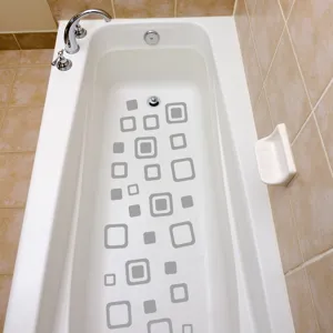 Macro view of grey geometric anti-slip stickers applied to a white bathtub interior.