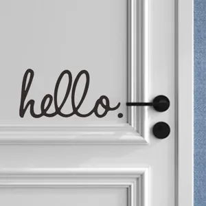 Primo piano di un adesivo murale nero 'hello.' applicato su una moderna porta bianca