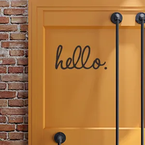 Primo piano di un adesivo da parete nero hello su una moderna superficie di porta arancione