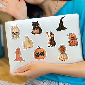 Lifestyle view of vintage Halloween stickers featuring pumpkins and ghosts on a laptop.