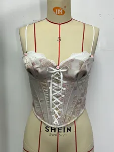 Detail view of floral embroidered lace corset top with white ribbon lace up and thin straps.