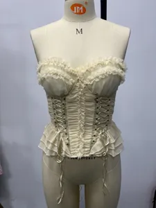 Dettaglio corsetto bustier beige con volant, allacciatura frontale e stile vintage.