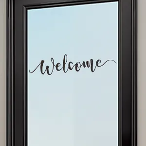 Detail view of a black cursive 'Welcome' wall sticker on a glass door surface