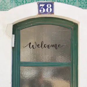 Macro detail of the elegant 'Welcome' cursive wall sticker applied to a glass door surface