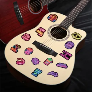 Detail showing neon motivational quote stickers applied to a wooden acoustic guitar