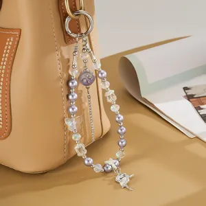 Charme élégant en perles violettes et cristaux avec danseuse sur un sac à main beige.