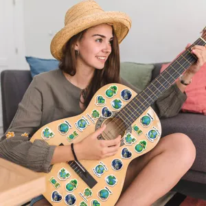 Decorative Earth Day stickers with environmental themes applied to an acoustic guitar