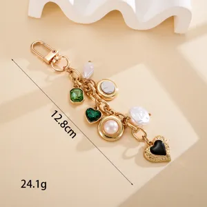 Detailed macro view of vintage gold keychain with heart and emerald stone charms, 12.8cm long.