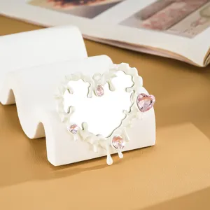 Dettaglio dello specchio a cuore liquido bianco con strass rosa brillanti.