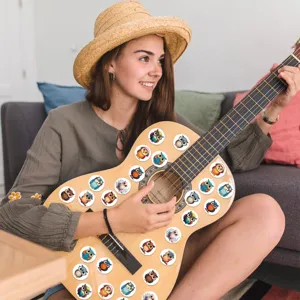 Vibrant cartoon owl stickers applied to an acoustic guitar in a cozy lifestyle setting