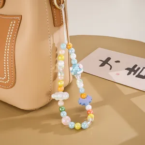 Colorful beaded phone strap with pixel heart and cloud charms on a tan leather bag