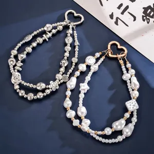 Primer plano de correas de muñeca para móvil con perlas, cuentas de plata y corazón.