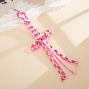 Detailaufnahme eines handgefertigten rosa-weißen Taschenanhängers aus Nylonkordel.