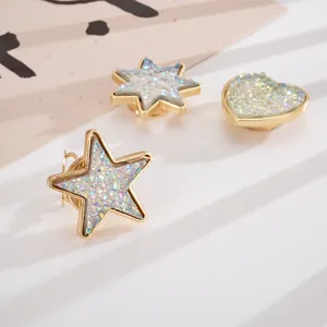 Close-up detail of gold heart and star cufflinks featuring iridescent crushed stone inlays