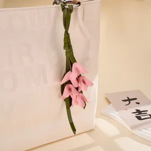 Detaillierte Nahaufnahme eines rosa PU-Leder Blumen Taschenanhängers an einem beigen Shopper