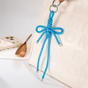 Detail van een handgeweven blauwe nylon strikhanger bevestigd aan een crème handtas