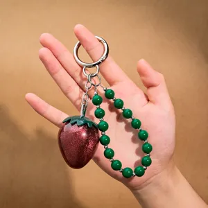 Detailansicht eines Glitzer-Erdbeer-Schlüsselanhängers mit grüner Perlenkette und Metallring