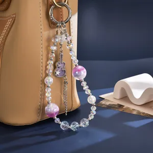 Detailed view of iridescent beaded bag charm with guitar pendant hanging on a bag