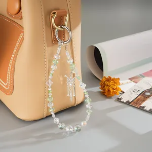Detailed macro shot of a crystal beaded butterfly bag charm on a tan leather purse