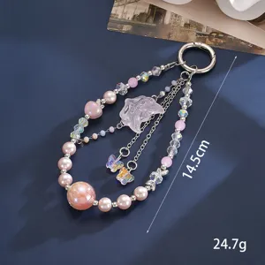 Detailed view of a beaded phone charm with pink pearls and butterfly pendants.