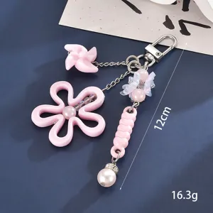 Detailaufnahme eines rosa Schlüsselanhängers mit Blumen und Windrad, 12 cm lang, 16,3 g schwer.