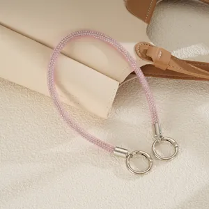 Detail of pink sparkling mesh strap with silver clasps on a beige leather bag background