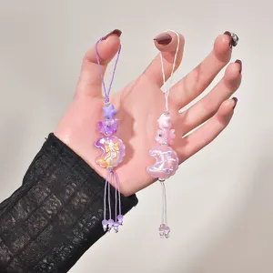 Candy-colored embossed moon charms with flower beads and tassels on a hand detail view