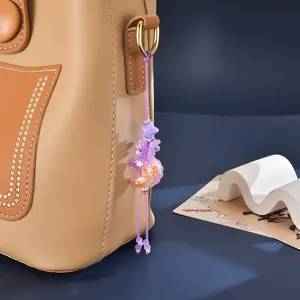 Close-up of candy-colored moon and flower beaded charm hanging on a tan leather bag
