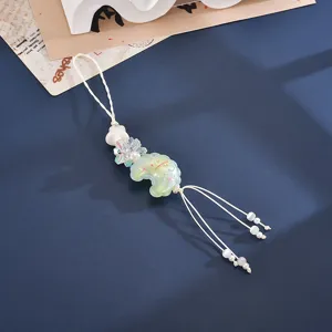 Macro detail of a candy-colored embossed moon charm with floral beads and tassels