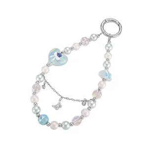 Close-up of a blue and white beaded phone strap with delicate heart and butterfly charms