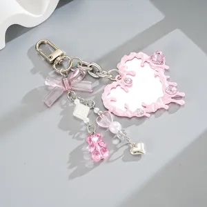 Llavero de espejo corazón fluido rosa con dijes de osito y lazo para bolsos.