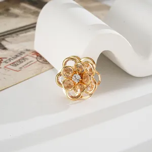Primo piano di un ciondolo camelia dorata con scintillanti cristalli champagne per DIY