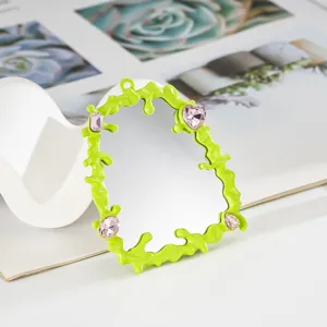 Vista dettagliata di una cornice a specchio verde neon fluido con accenti di gemme rosa DIY.