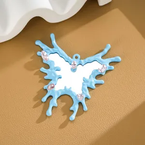 Close-up of a blue irregular butterfly mirror charm with pink gemstones and glossy finish