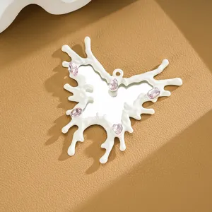 Close-up of butterfly pendant with mirror center, pink gems, and white drip frame