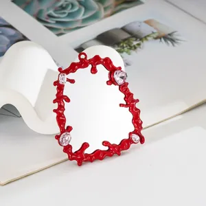 Vista dettagliata di un accessorio specchio liquido rosso fai-da-te con gemme rosa a cuore